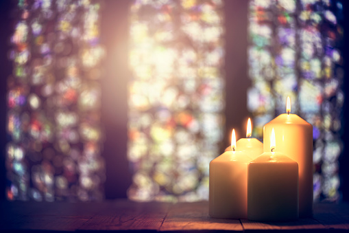 candles burning with stained glassed behind